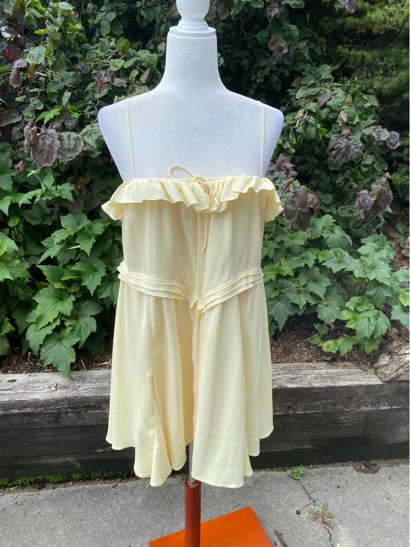 Light yellow strapless dress with ruffled neckline and flowy skirt on white mannequin.