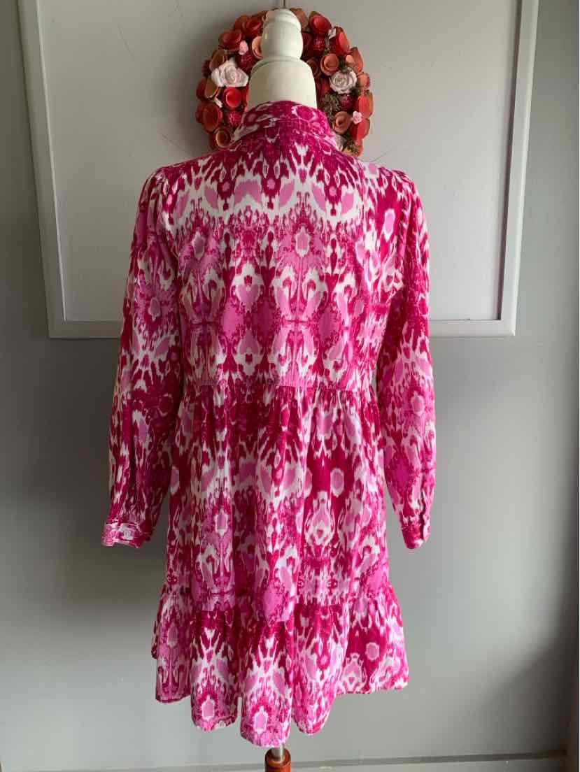 Pink and white patterned long-sleeve dress with tiered skirt on mannequin.