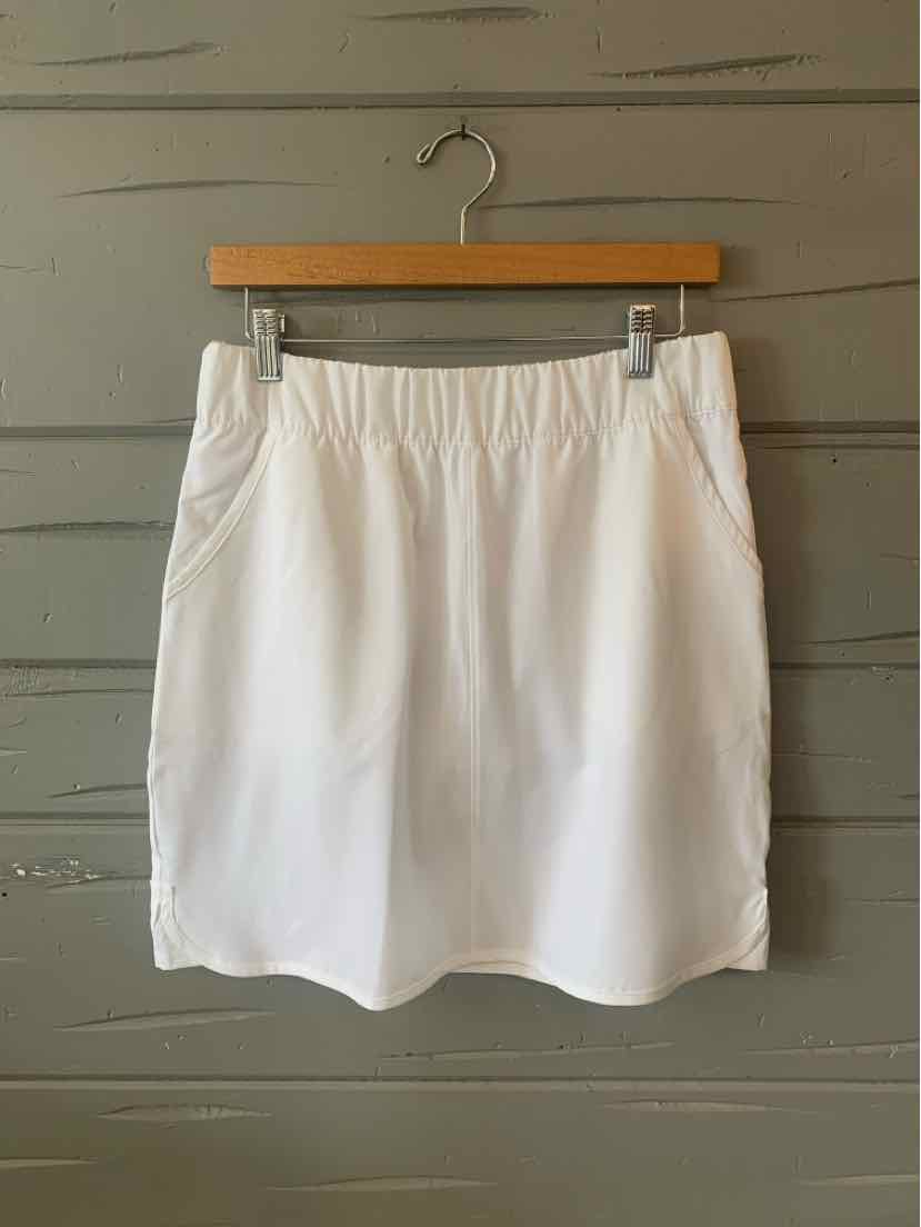 White women's skort with elastic waistband and front seam detailing hanging on wooden hanger.