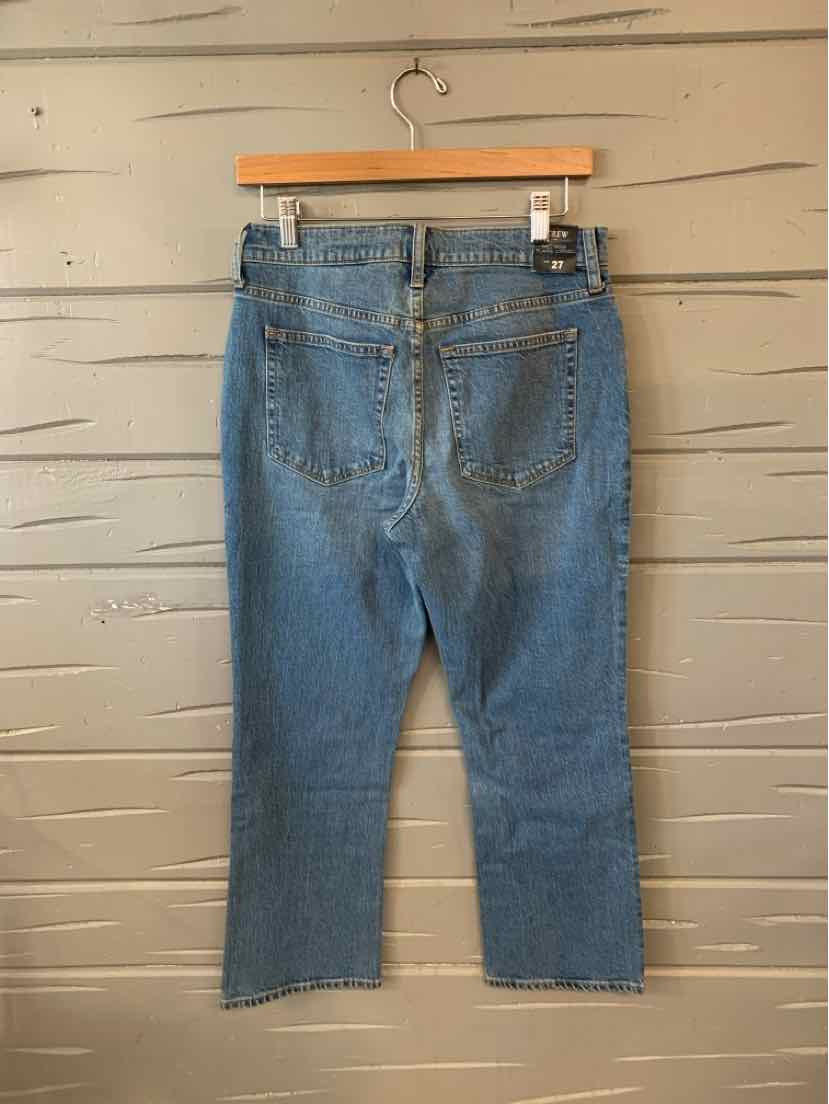 High-waist blue denim jeans with back pockets and a straight leg cut hanging on wooden hanger.