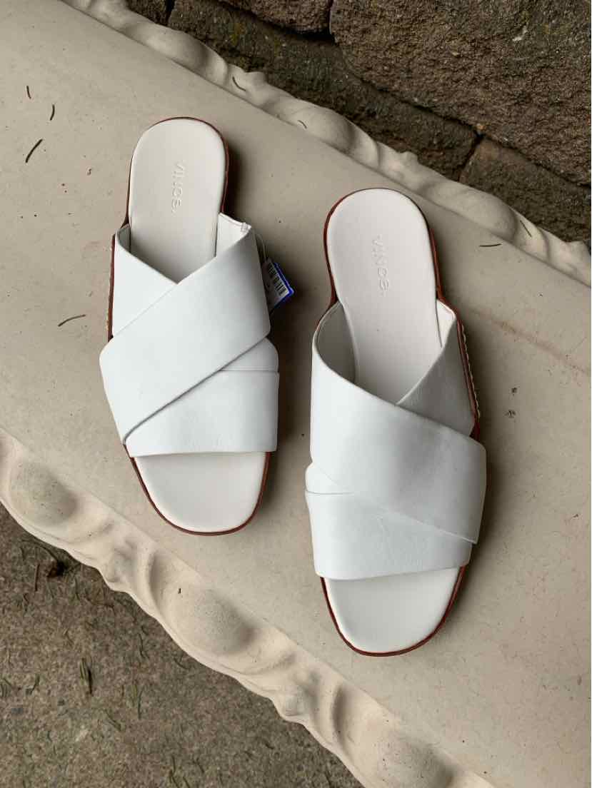White leather slip-on sandals with wide crisscross straps and flat soles, size 9.