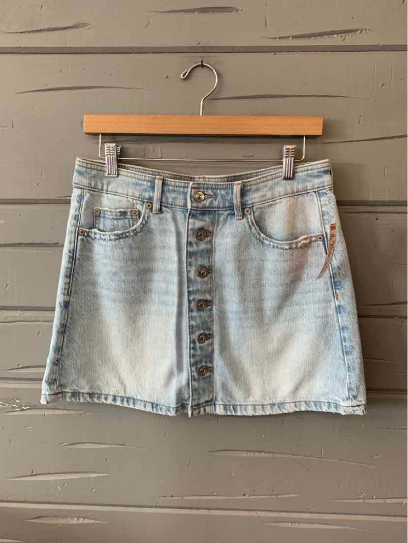 Light wash denim mini skirt with front button closure and five-pocket design.