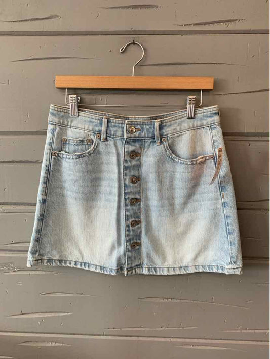 Light wash denim mini skirt with front button closure and five-pocket design.