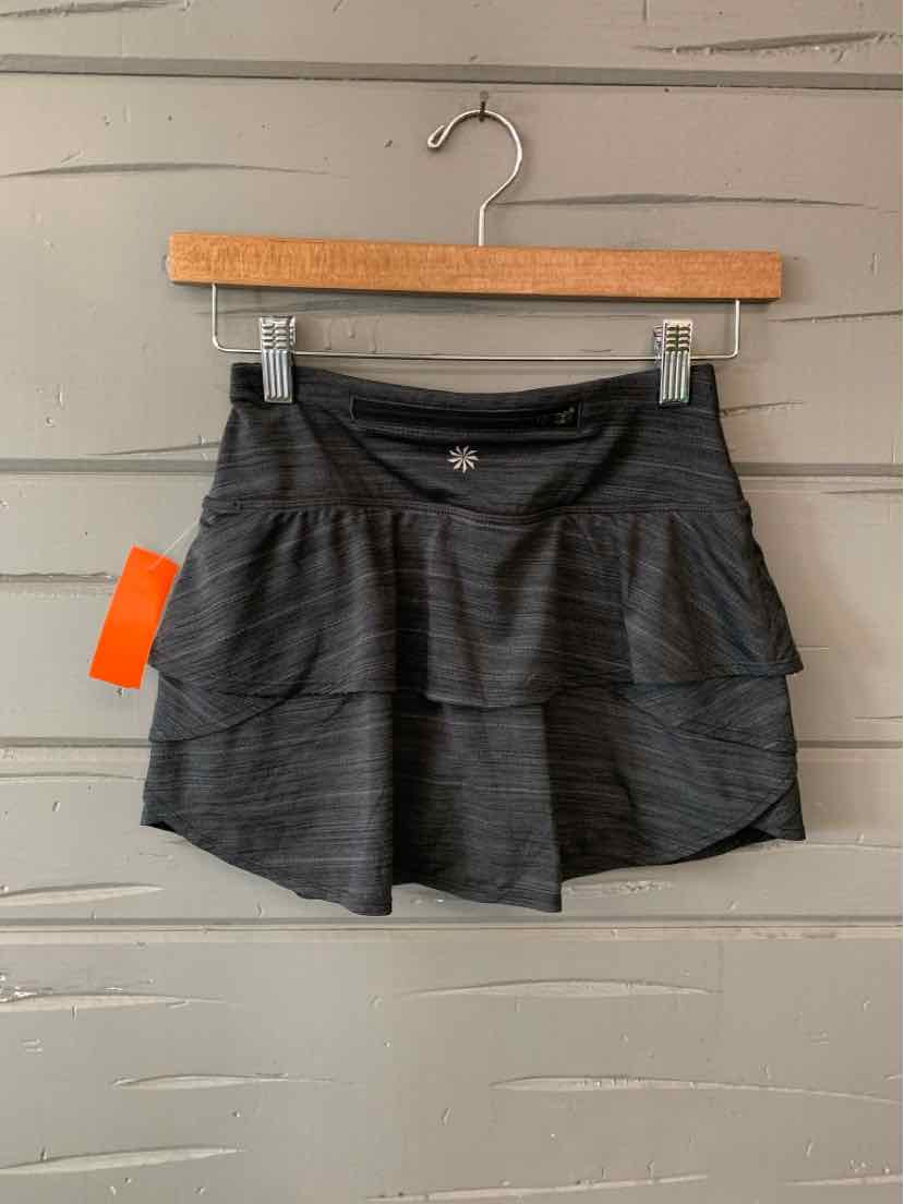 Dark gray tiered athletic skirt with wide waistband and lightweight fabric hanging on wooden hanger.