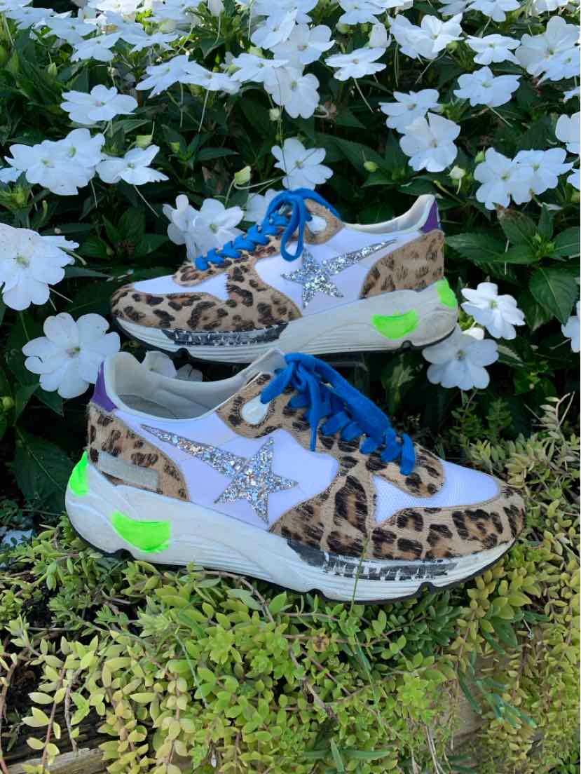 Low-top sneakers with leopard print suede, white leather star logo, blue laces, and neon green sole accents.