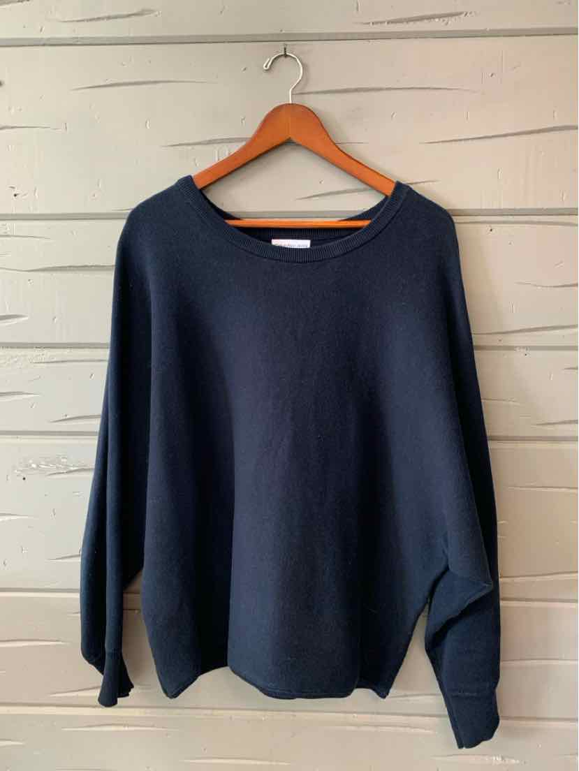 Black long-sleeve crewneck sweatshirt with relaxed fit hanging on wooden hanger.