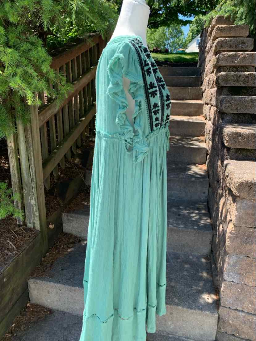 Light teal maxi dress with floral embroidery and long sleeves on mannequin outdoors.
