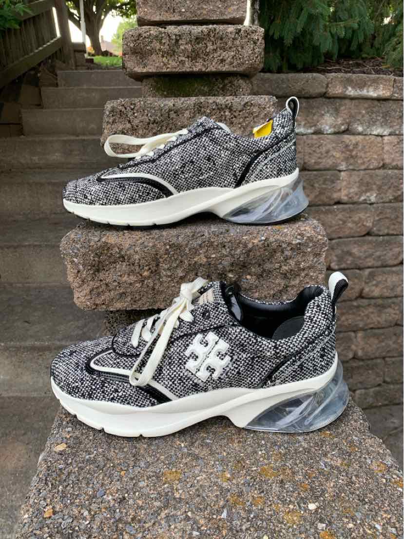 Black and white tweed Tory Burch sneakers with thick white soles, lace-up front, and logo detail on side.