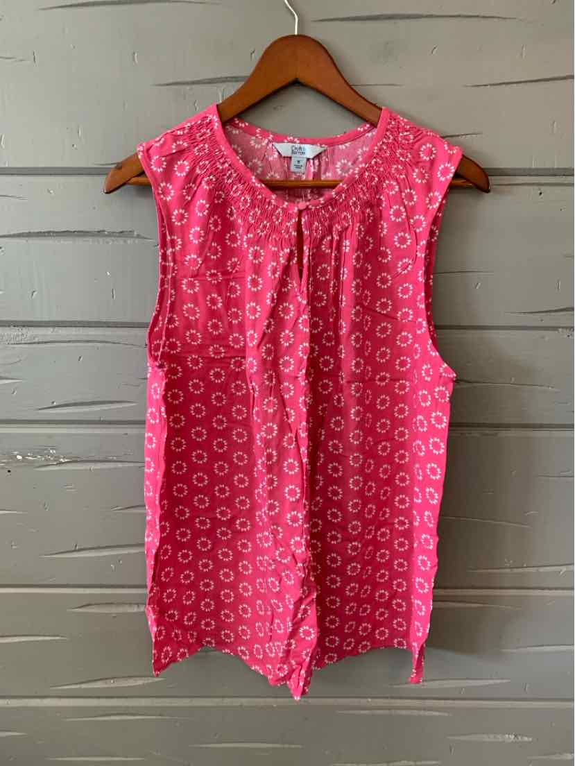 Sleeveless pink blouse with white floral pattern and tie neck detail on wooden hanger.