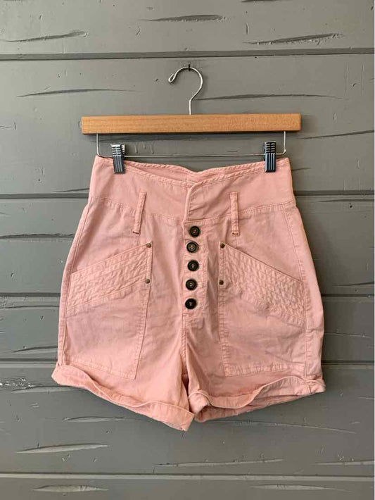 High-waist dusty pink shorts with front button closure and large side pockets, made of textured fabric.