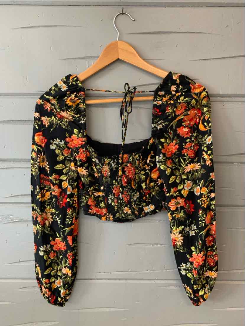 Black cropped blouse with orange and yellow floral print, long puff sleeves, and tie neck detail.