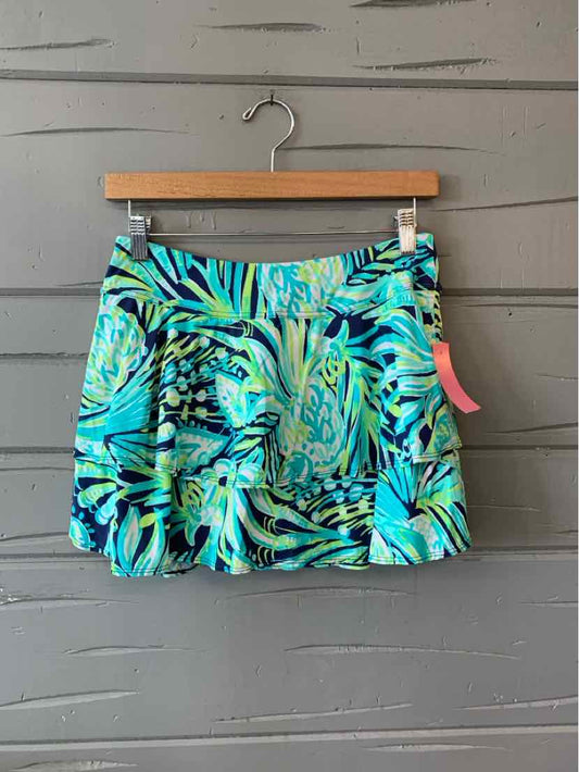 Blue and green tropical print women's skirt with ruffled hem on wooden hanger.