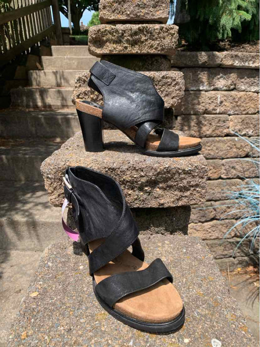 Black leather high-heeled sandal with crisscross straps and ankle zipper, size 9.