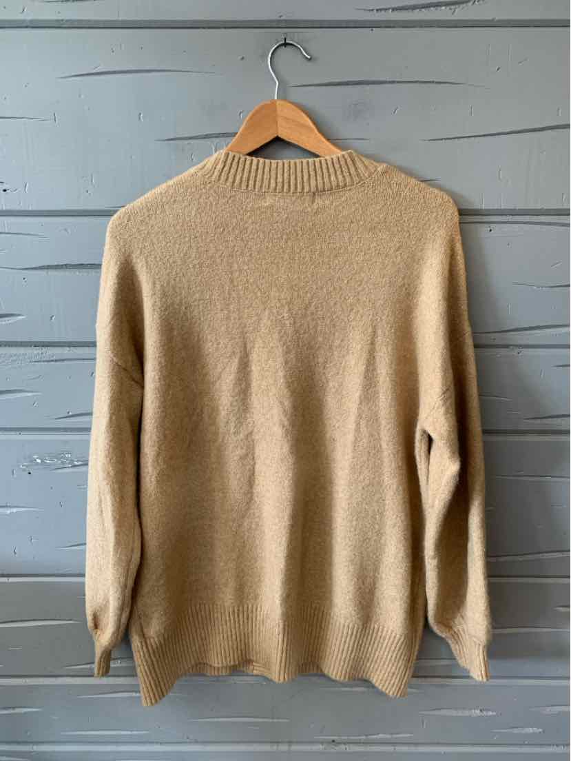 Tan knit sweater with long sleeves and a ribbed crew neck, displayed on a wooden hanger.