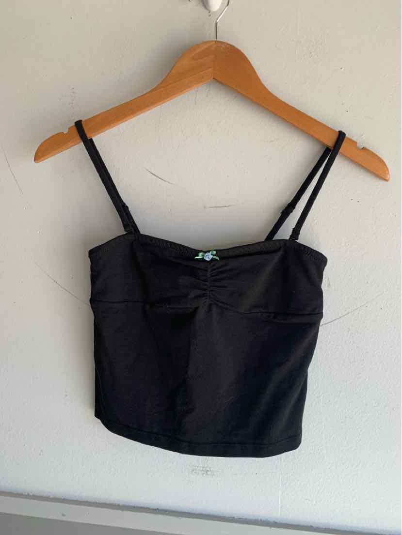 Black cropped camisole with thin adjustable straps on wooden hanger against white wall.
