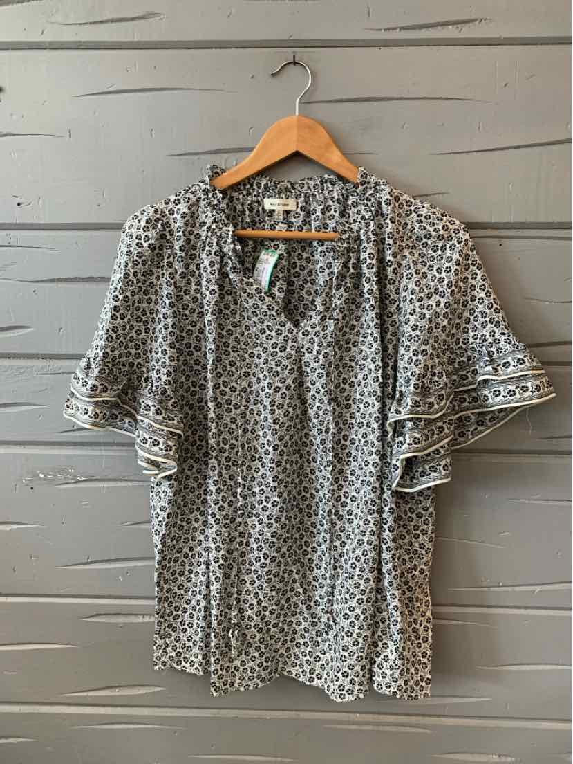 Black blouse with white polka dots, short ruffled sleeves, and a small front tie at the neckline.