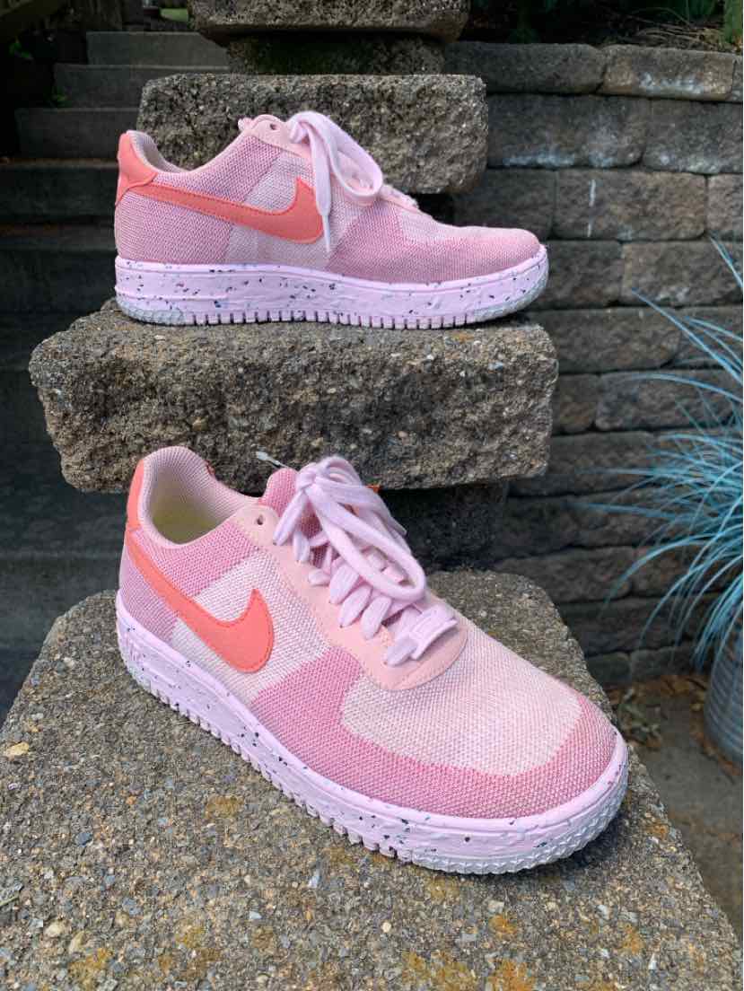Pink Nike sneakers with light pink mesh and suede panels, solid pink swoosh, and white rubber sole.