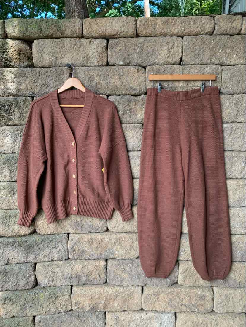 Brown knit cardigan with buttons and matching knit pants with elastic cuffs hanging on wooden hangers.