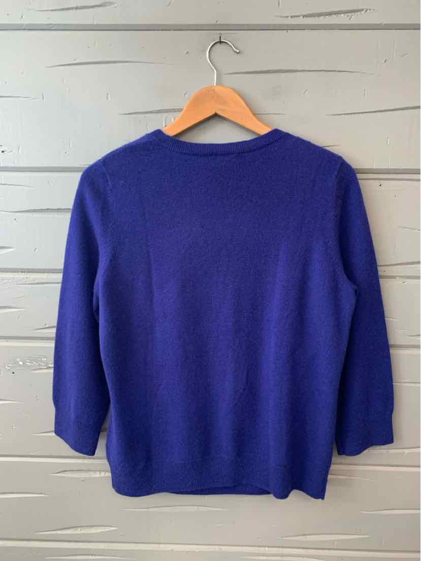 Women’s solid blue medium sweater with three-quarter sleeves hanging on wooden hanger.