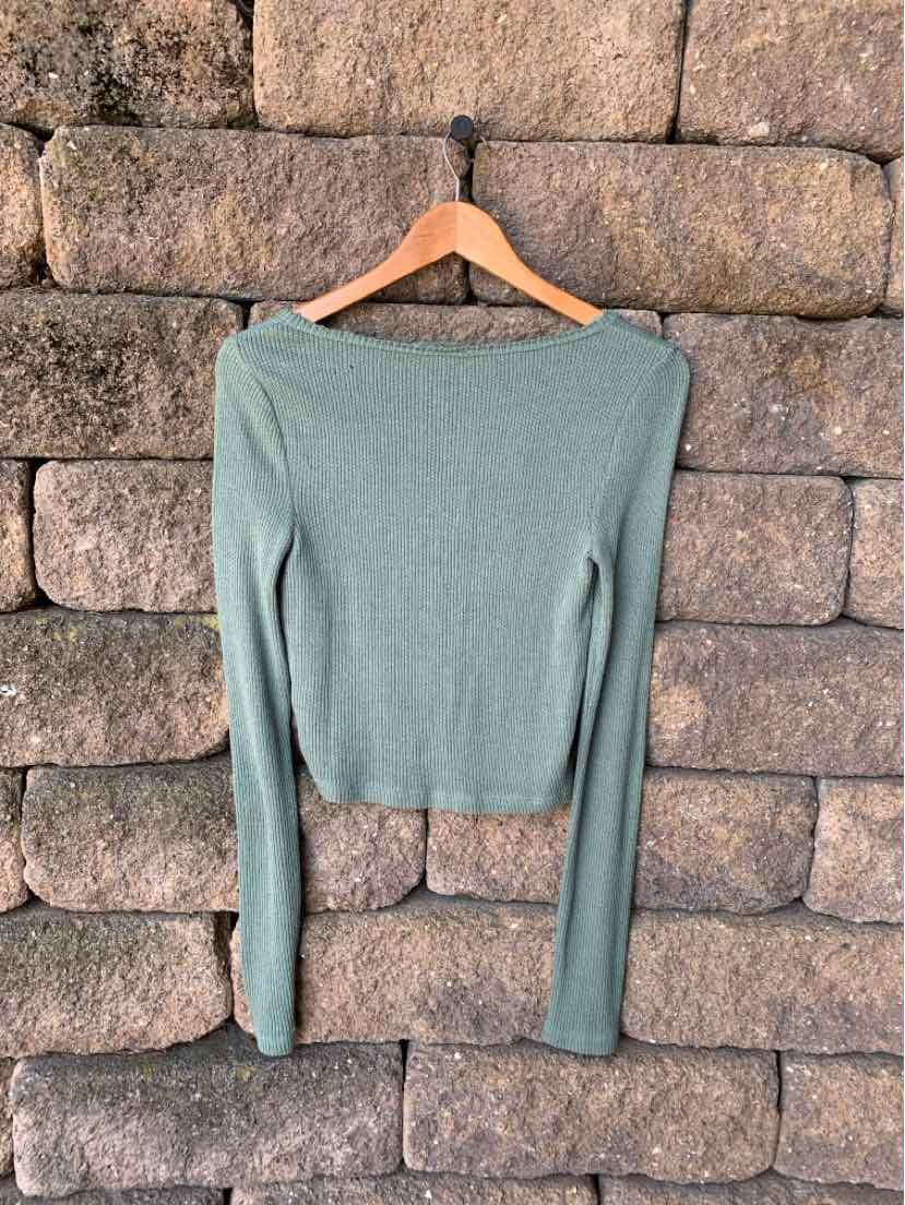 Light green ribbed long-sleeve cropped sweater with a boat neckline on wooden hanger.