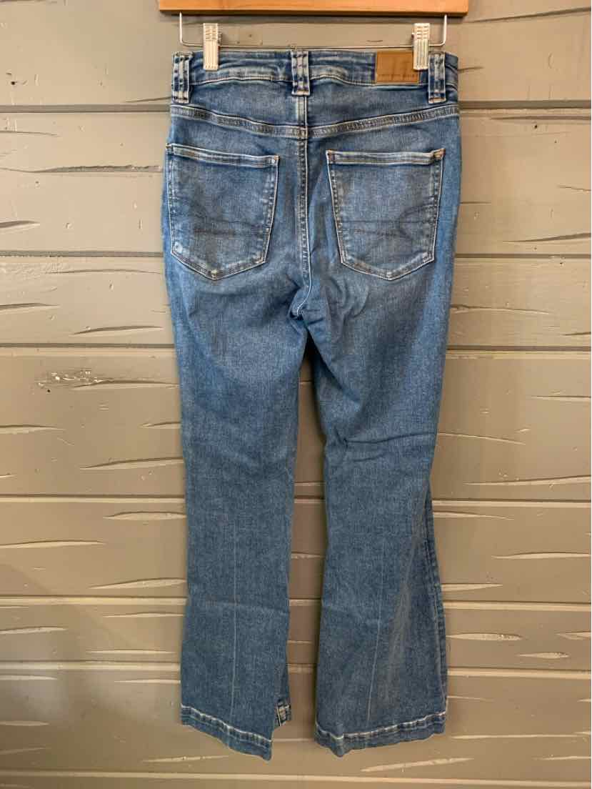 Light blue denim jeans with slight distressing, back pockets, and raw hem detailing.