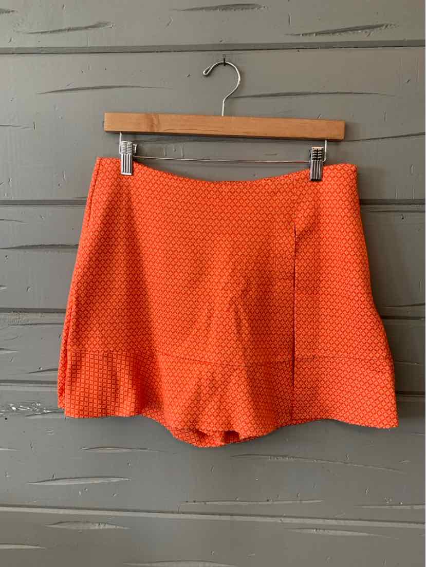 Orange patterned high-waist shorts with subtle diamond print hanging on wooden hanger.