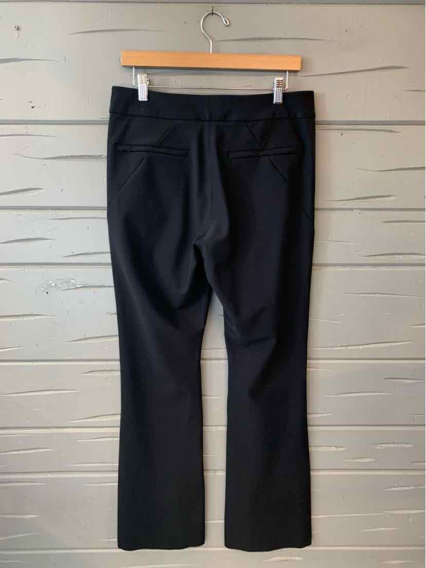 Black straight-leg pants with back welt pockets and fitted waistband hanging on wooden hanger.