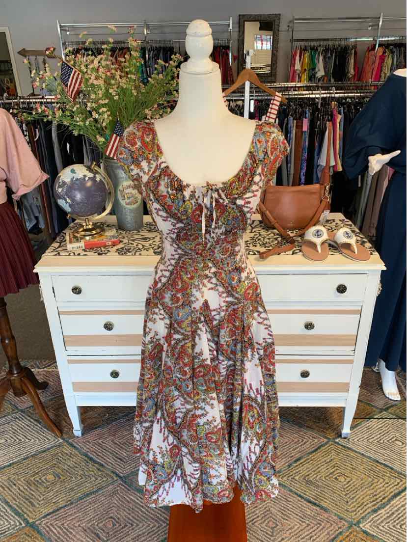 Sleeveless midi dress with multicolor paisley print, fitted bodice, and flared skirt on mannequin.