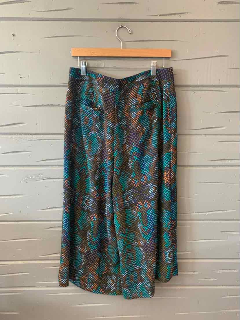 Teal wide-leg pants with snakeskin print and side pockets hanging on wooden hanger.
