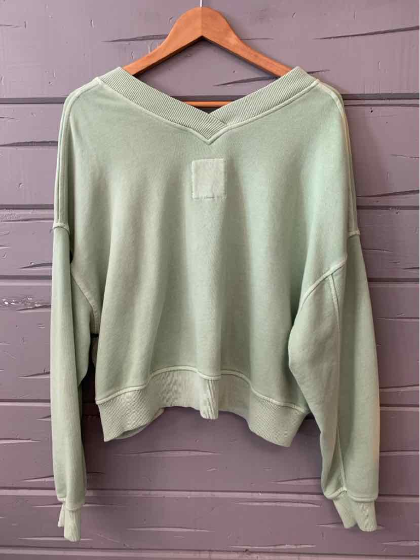 Light green long-sleeve crewneck sweatshirt with relaxed fit and dropped shoulders on wooden hanger.