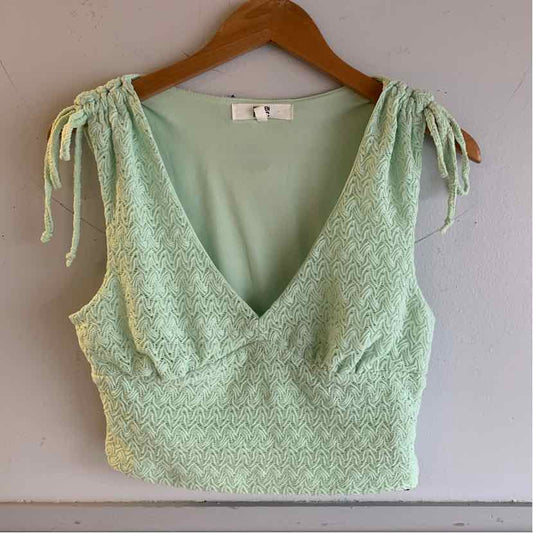 Mint green textured crop top with tie straps and deep V-neckline on wooden hanger.