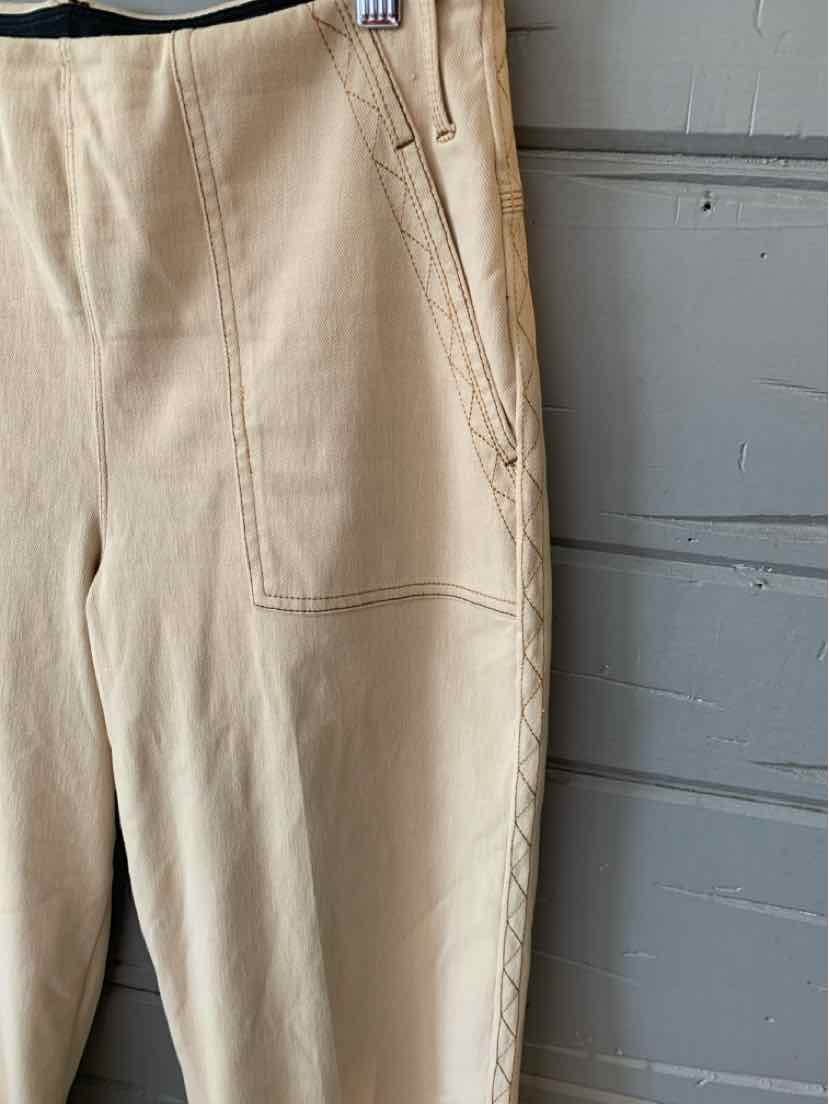 Tan slim-fit pants with front patch pockets and subtle seam detailing.