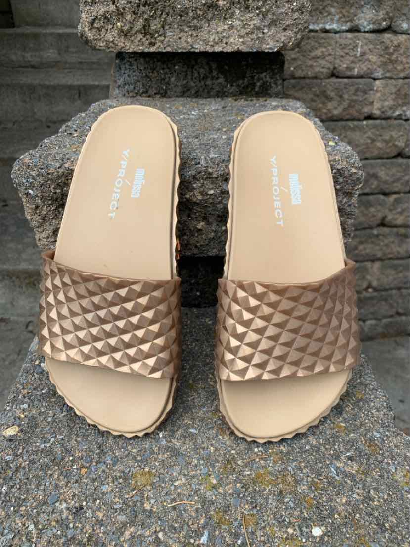 Metallic bronze slide sandals with quilted texture on wide straps and beige footbeds, size 7.
