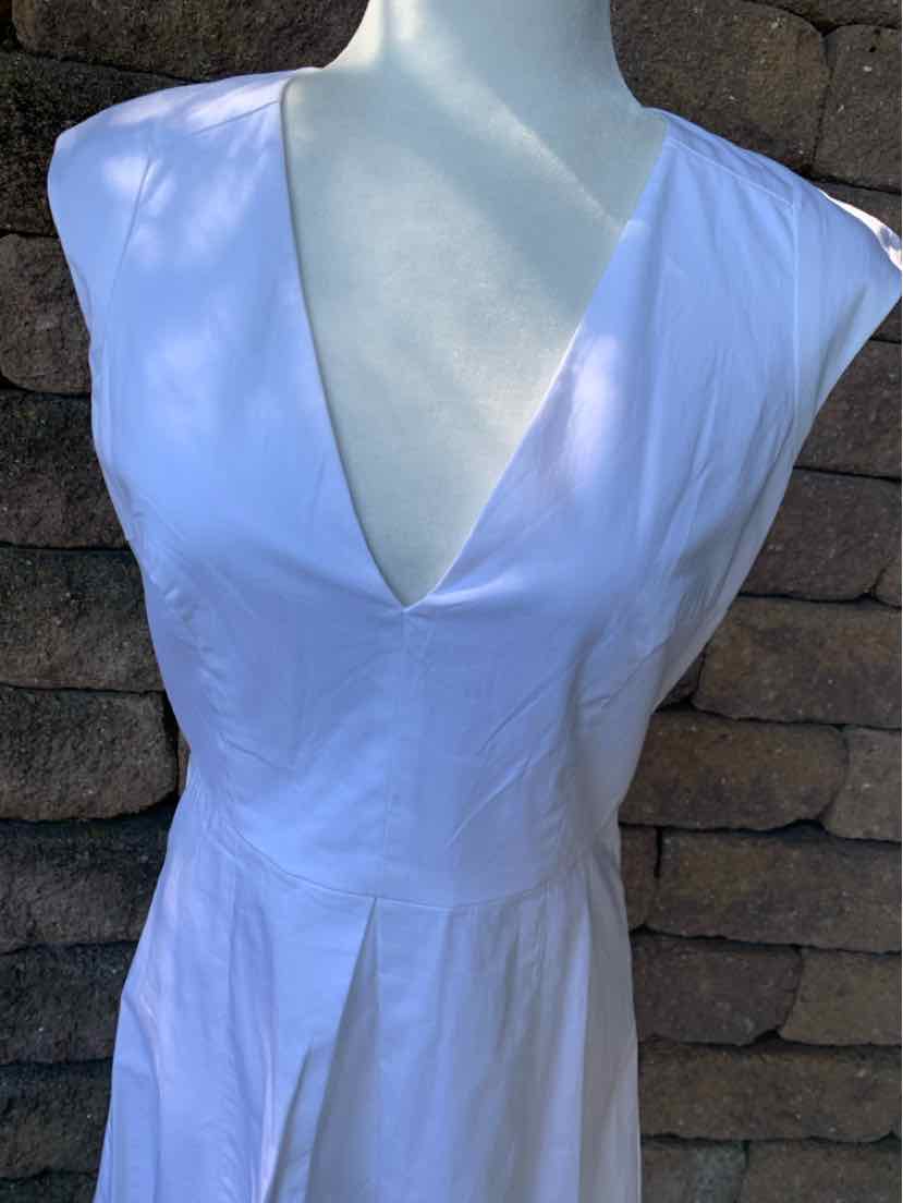 White sleeveless dress with deep V-neckline and fitted waist detail.