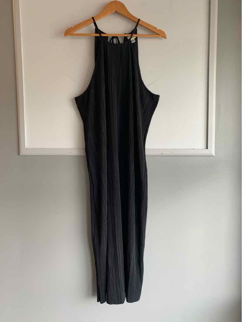 Black sleeveless wide-leg jumpsuit with adjustable straps and a relaxed fit hanging on wooden hanger.