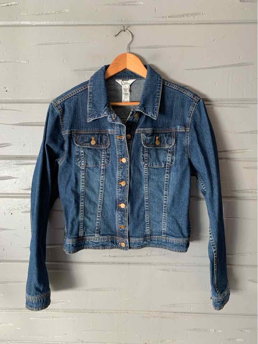 Medium-wash blue denim jacket with button front, pointed collar, chest pockets, and long sleeves.