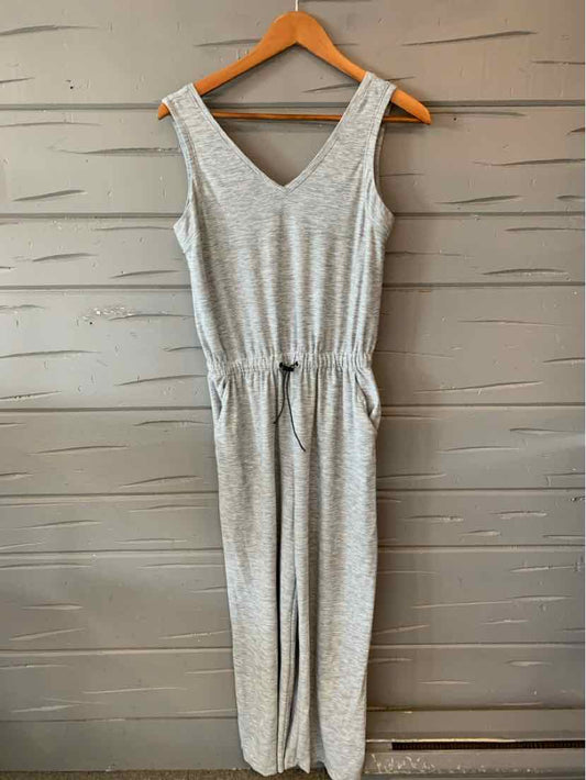 Light gray sleeveless jumpsuit with V-neck and elastic waistband on wooden hanger.