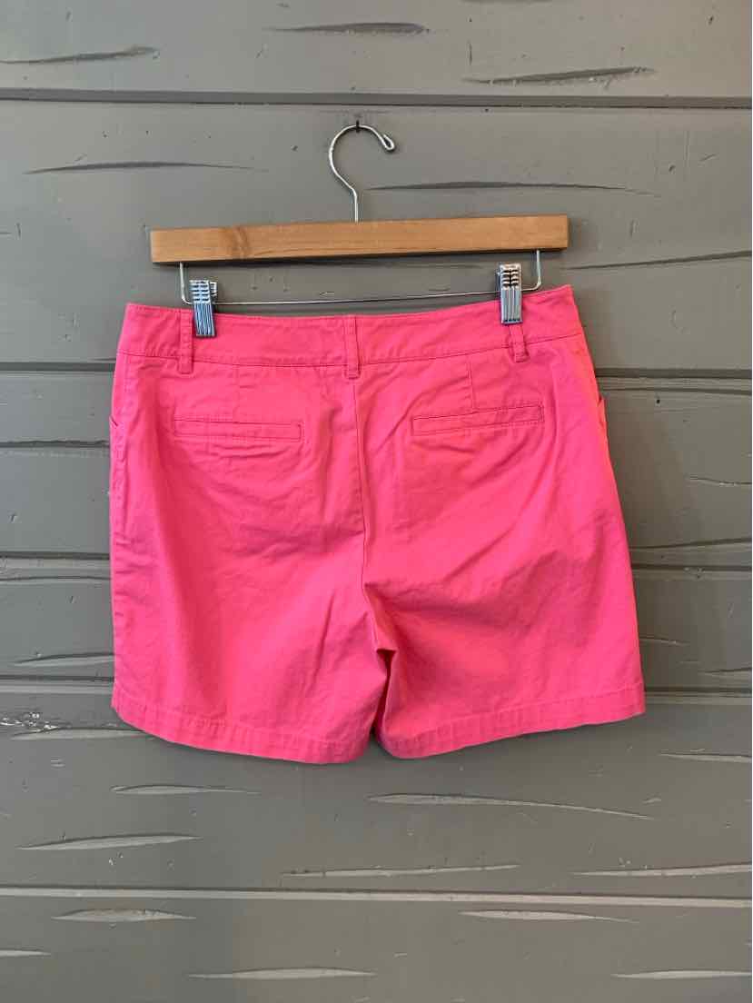 Pink tailored shorts in size 6P with rear pockets hanging on wooden hanger.