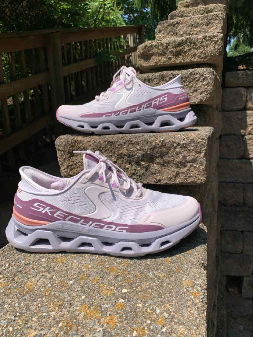 Light pink Skechers women's sneaker with mesh fabric, white sole with wave cutouts, and branded side panel.