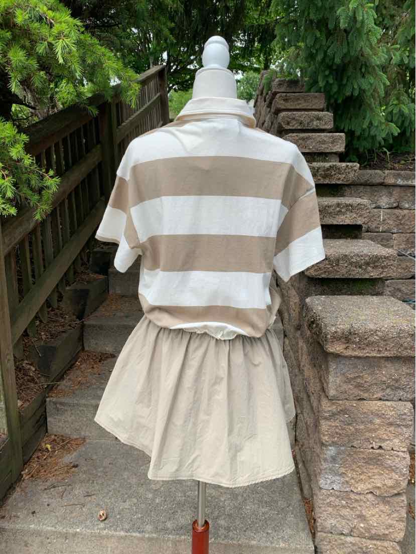 Tan and white striped short-sleeve shirt paired with a beige skirt displayed outdoors on a mannequin.