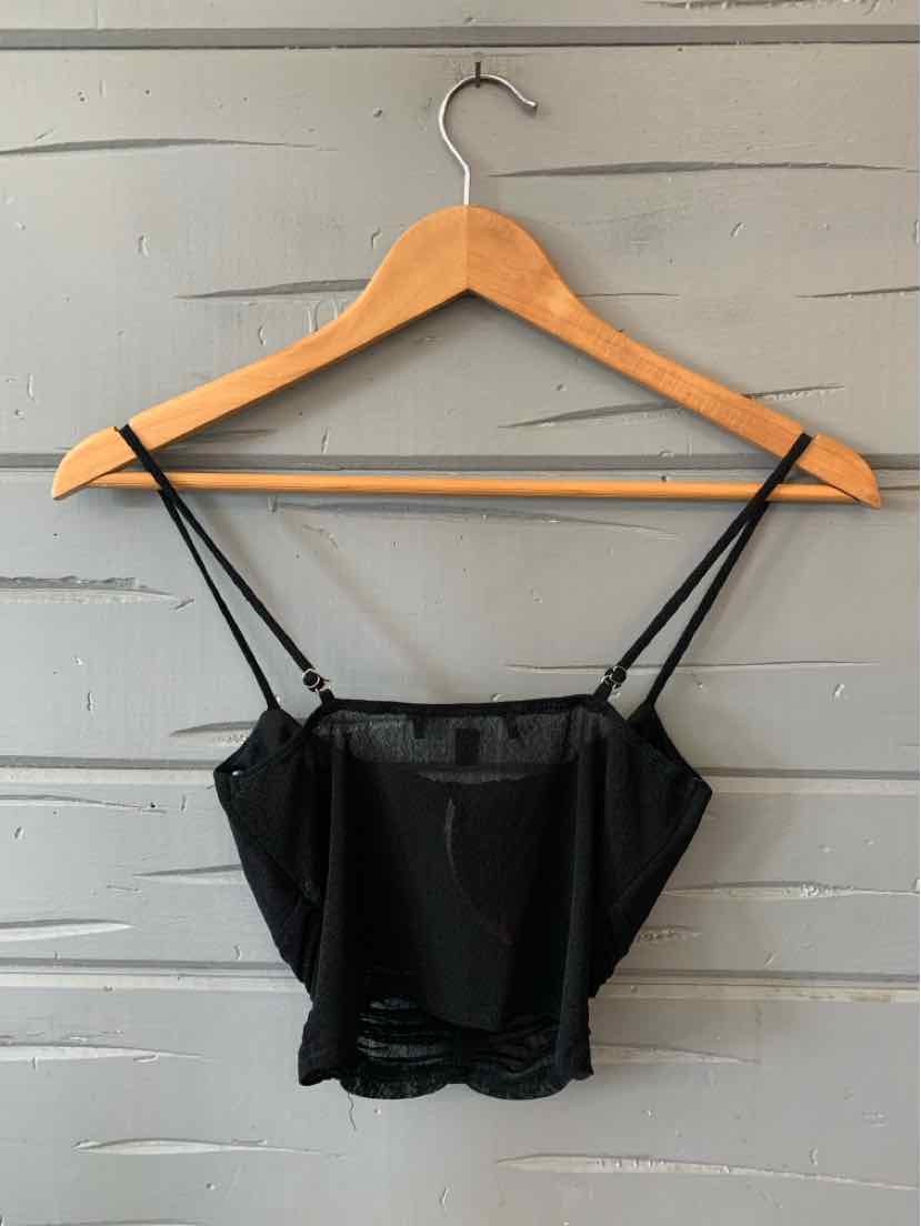 Black cropped camisole top with thin adjustable spaghetti straps and a straight neckline on wooden hanger against gray.