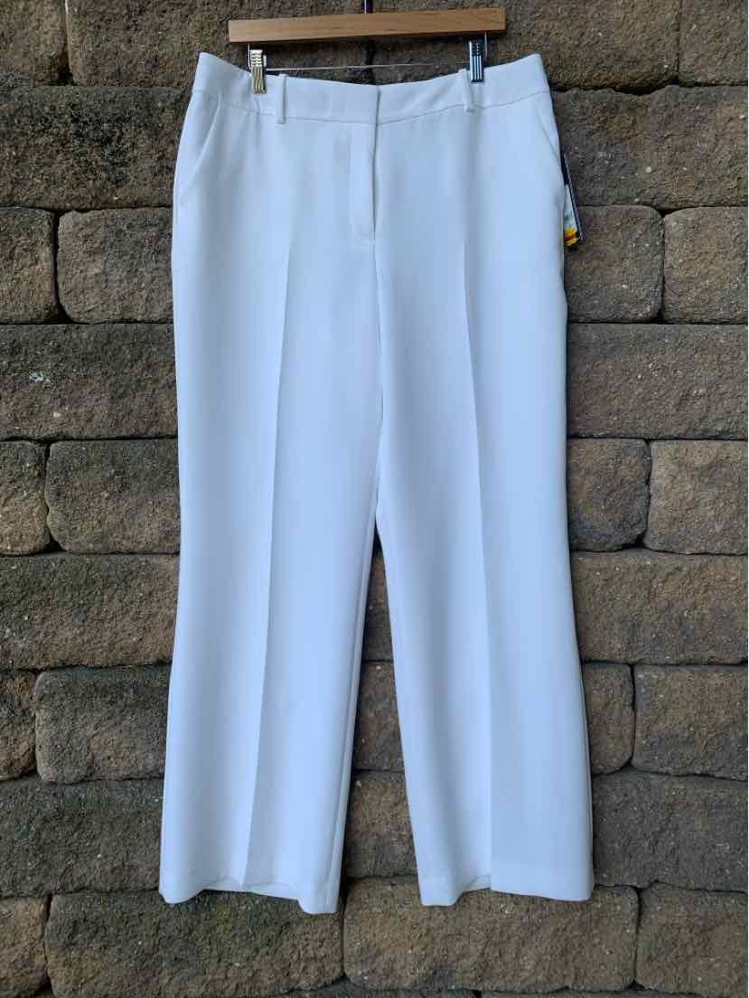 White straight-leg trousers with a high waist and belt loops hanging against a stone wall.