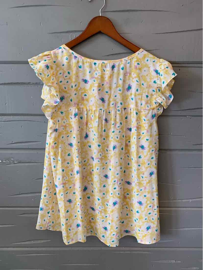 Yellow floral short-sleeve blouse with ruffled sleeves and loose fit hanging on wooden hanger.