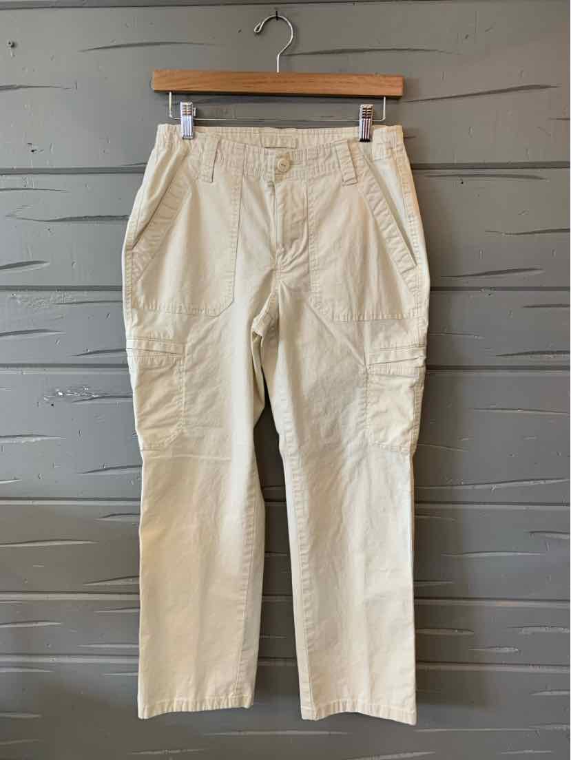 Tan straight-leg pants with front pockets and belt loops on wooden hanger against gray paneled wall.
