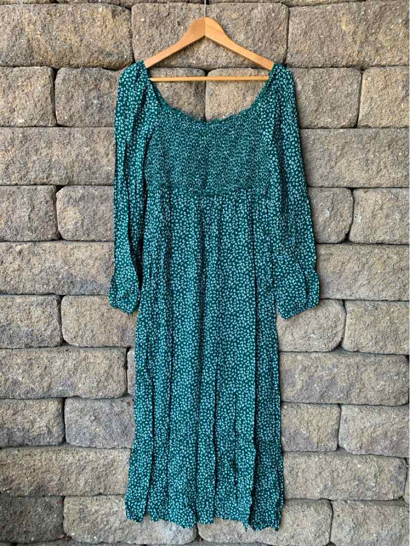 Green long-sleeve midi dress with floral print and elastic cuffs hanging on wooden hanger.