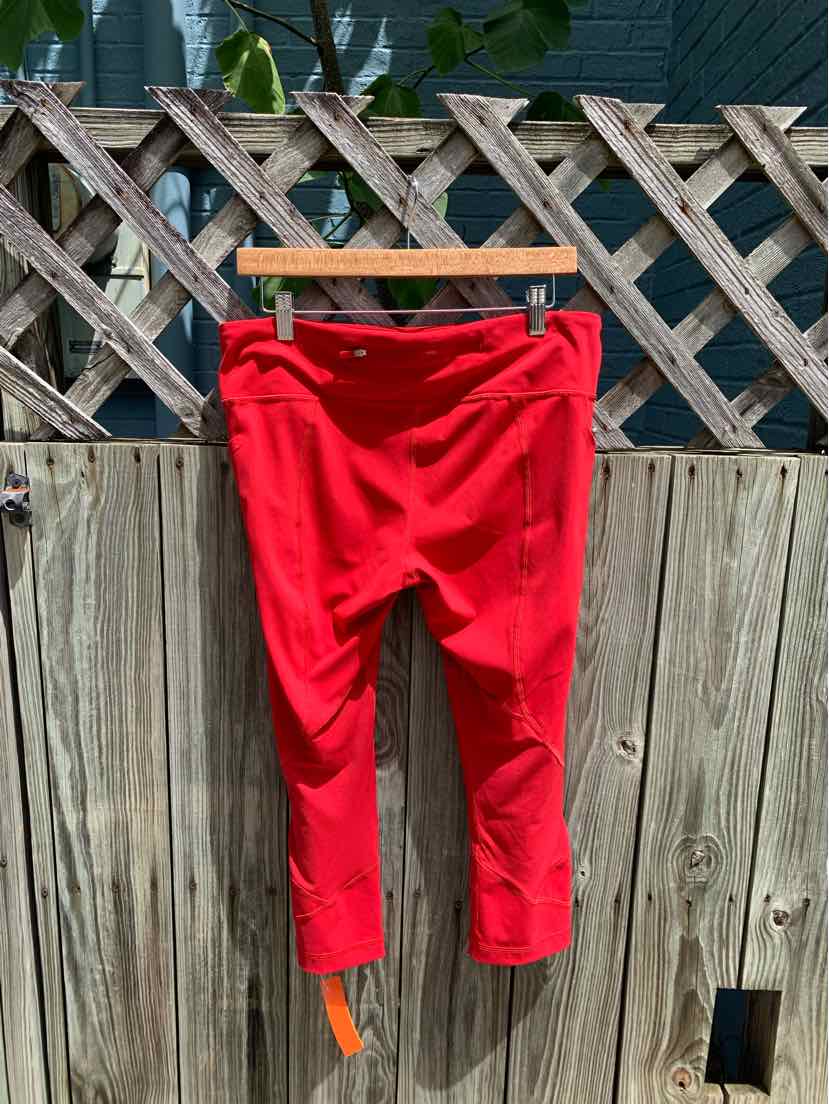 Bright red cropped leggings with high waistband and flatlock seams, size 12, hanging outdoors.