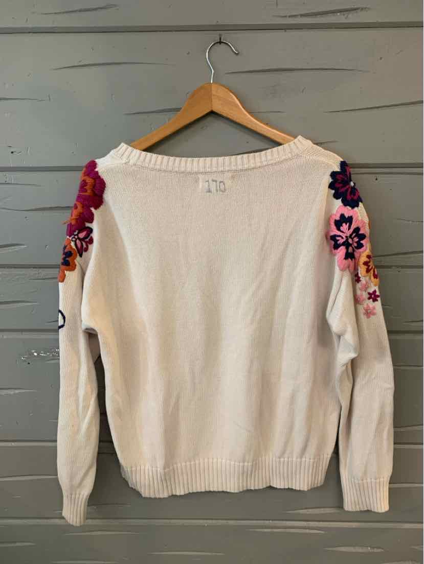 White knit sweater with long sleeves featuring large colorful floral embroidery on shoulders and upper arms.