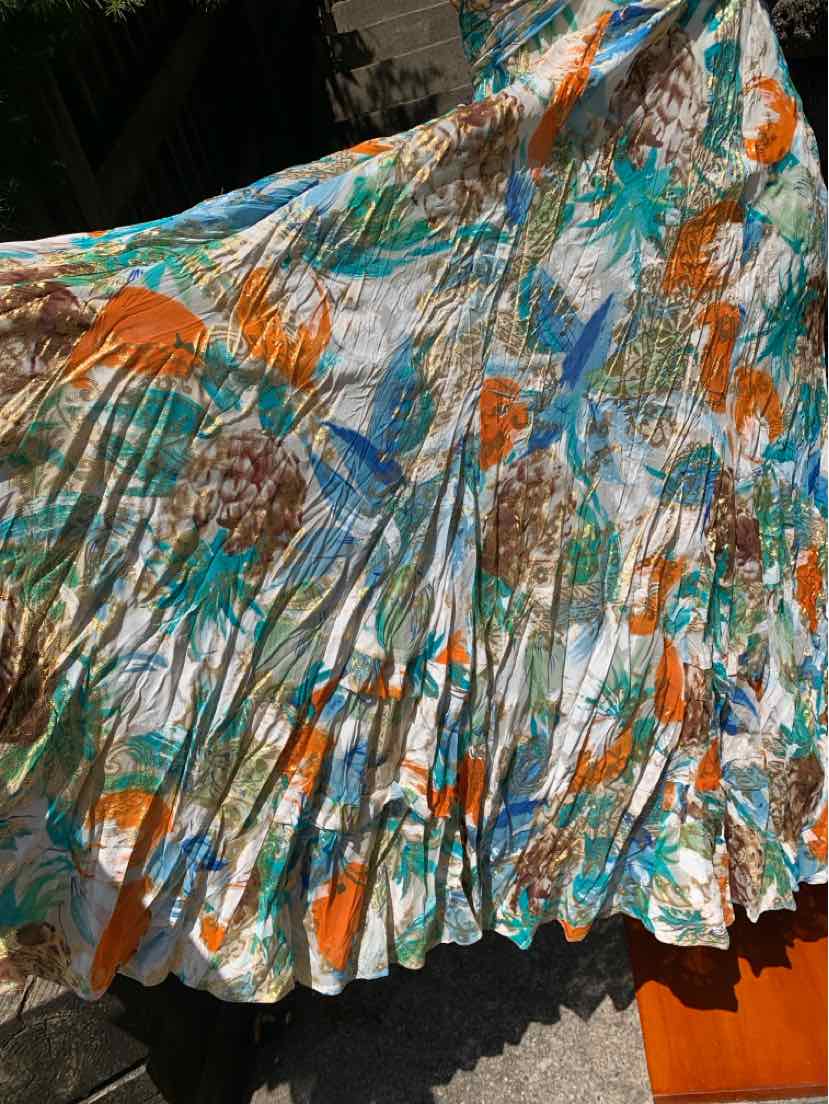 Pleated skirt with abstract floral print in orange, teal, brown, and white colors.