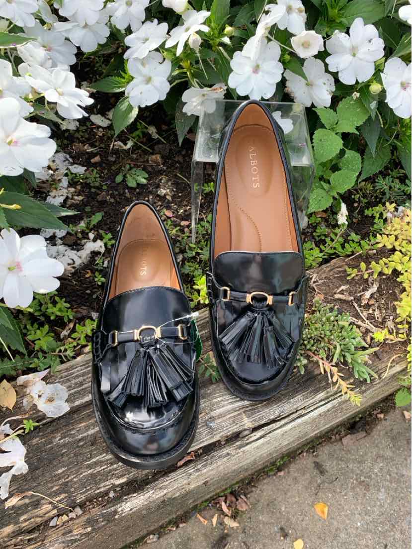 Black leather tassel loafers with gold-tone horsebit detail, rounded toe, and low heel.