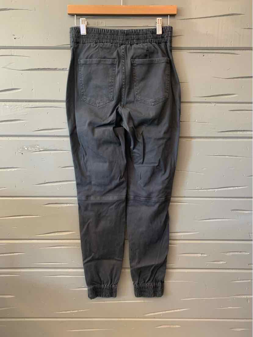 Gray women's denim jeans with elastic cuffs hanging on wooden hanger against light wood backdrop.